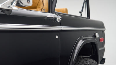 Side view of black Classic Ford Bronco door with tan leather interior and steering wheel