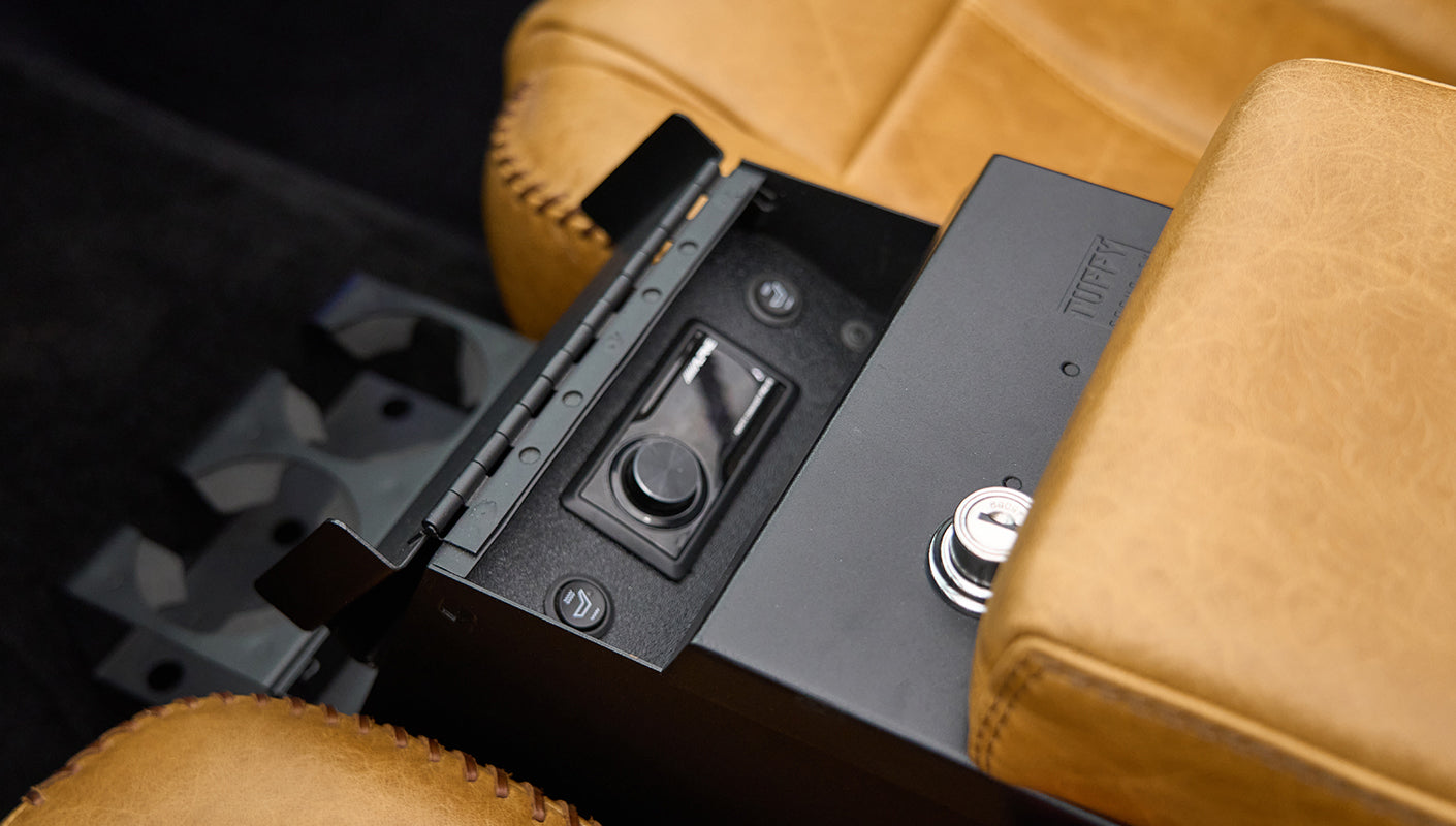 Open black console box revealing audio control switches between tan leather seats
