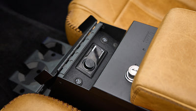 Open black console box revealing audio control switches between tan leather seats