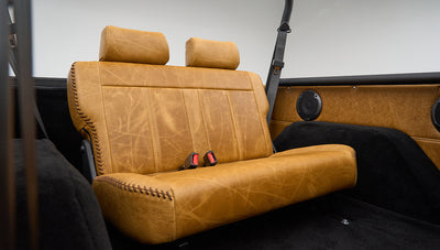 Rear view of Classic Ford Bronco tan leather bench seat with speakers and black roll bar