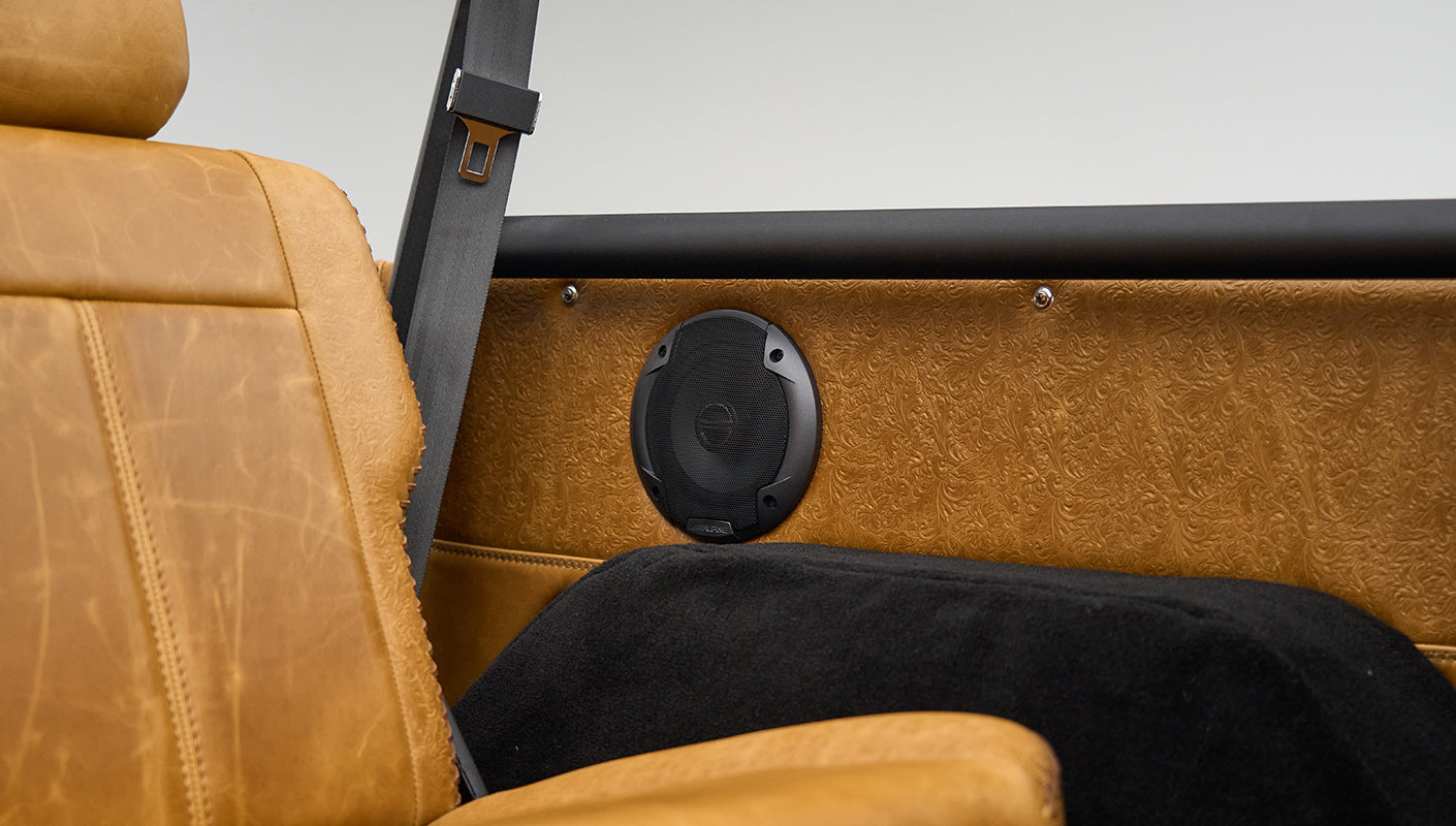 Tan leather seat back with black speaker and embossed leather panel behind it