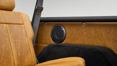 Tan leather seat back with black speaker and embossed leather panel behind it