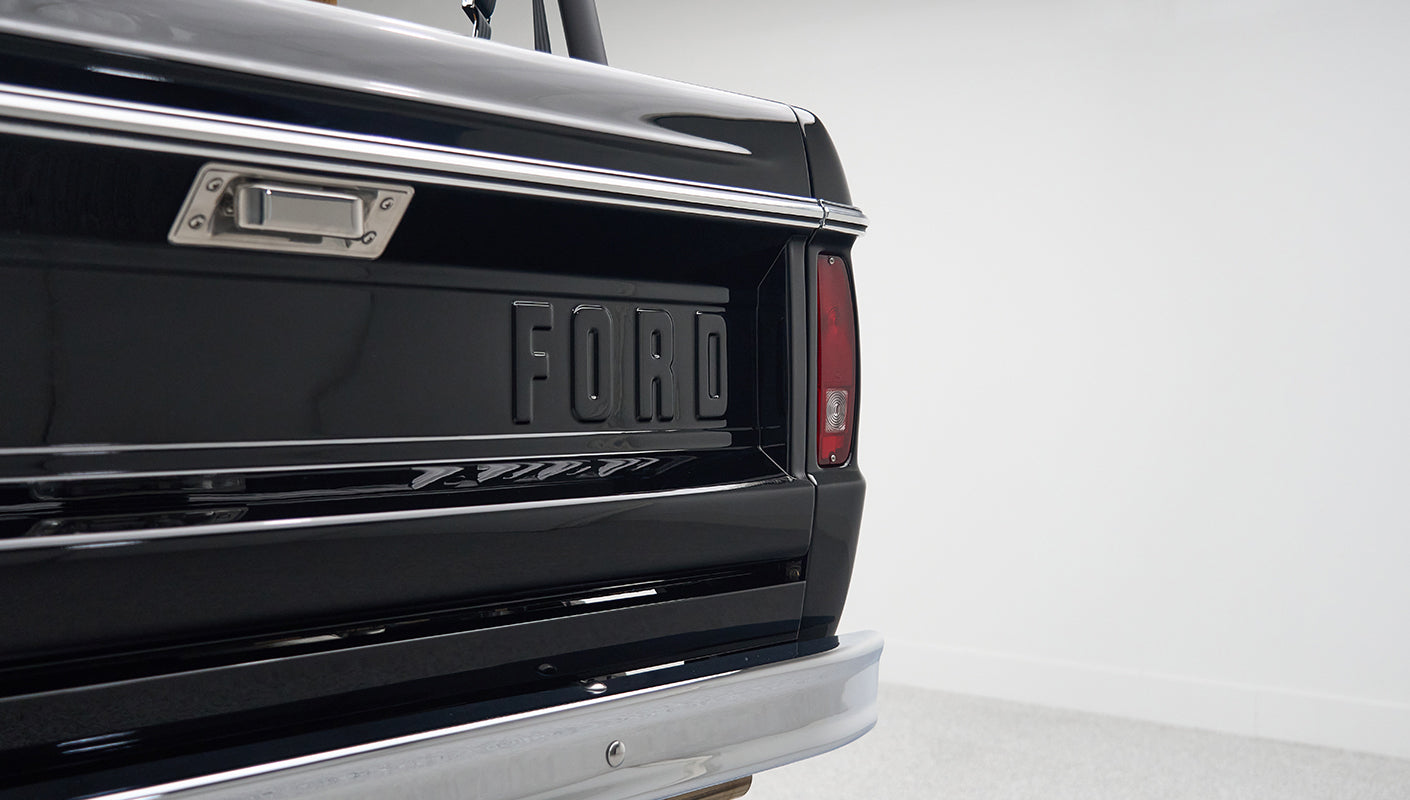 Rear tailgate of Classic Ford Bronco painted black with raised FORD lettering and red tail light