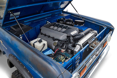 Open hood displaying a clean engine bay with a 5.0 badge engine inside a blue Classic Ford Bronco