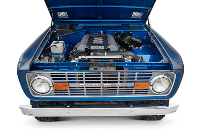 Head-on front view of a blue Classic Ford Bronco with chrome grille and round headlights