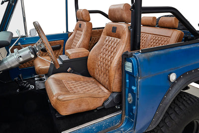 Driver side front interior seats in brown leather with diamond stitching inside a blue Classic Ford Bronco