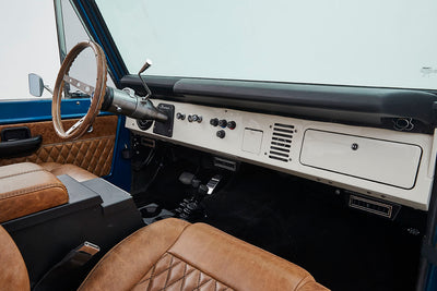 Interior view showing dashboard, steering wheel, and brown quilted seats in Classic Ford Bronco