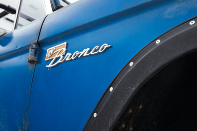 Close-up of blue Classic Ford Bronco door with bronze Sport Bronco emblem