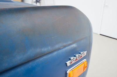 Close-up of blue Classic Ford Bronco front fender showing 302 emblem and fatigued paint
