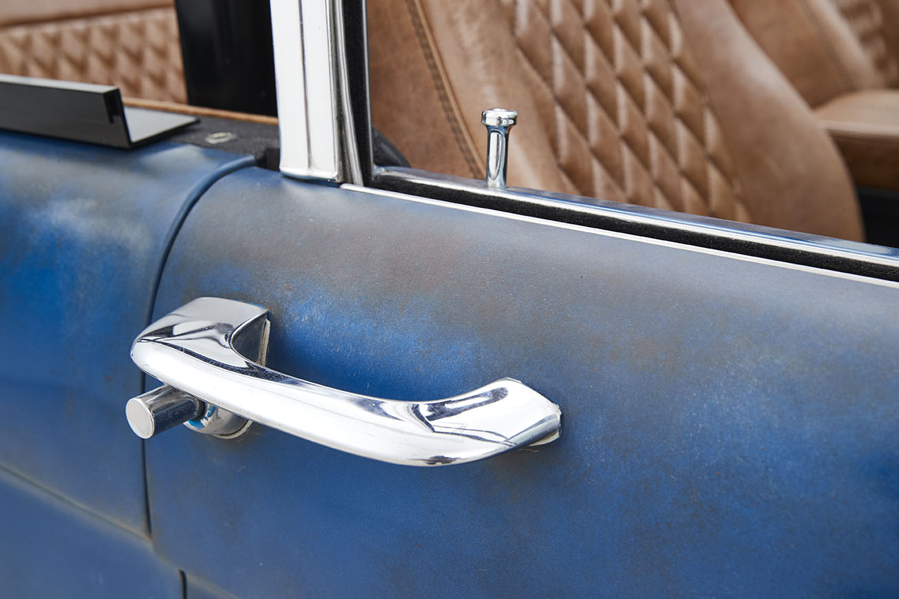 Close-up of chrome door handle and blue patina door panel of Classic Ford Bronco
