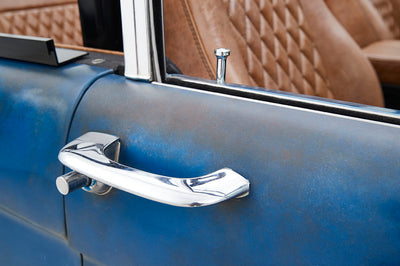Close-up of chrome door handle and blue patina door panel of Classic Ford Bronco