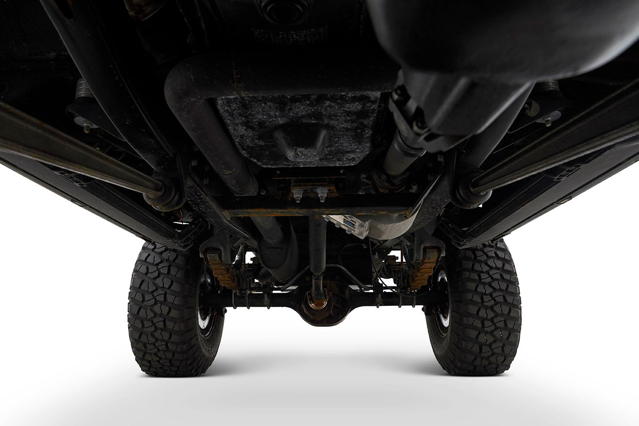 Underside view of off-road vehicle chassis and tires against white background