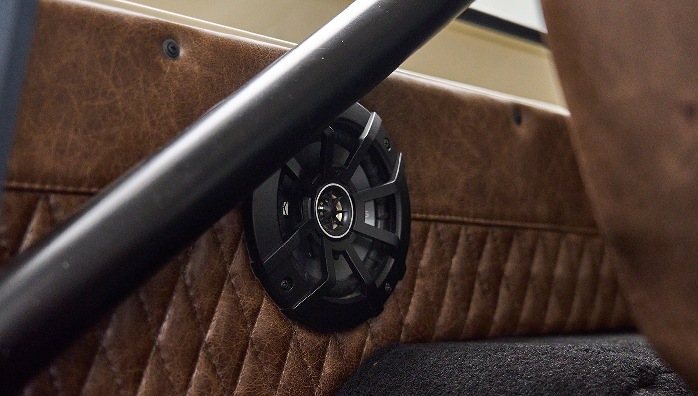 Black circular speaker mounted on tan quilted door panel inside a Classic Ford Bronco
