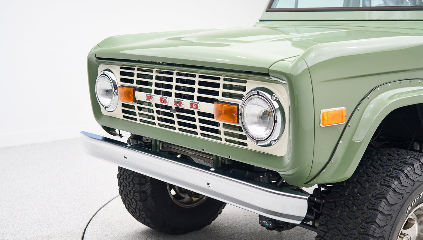 Classic Ford Bronco in boxwood green with white roof, rear view centered on white background.