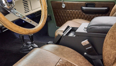 Interior view showing wooden steering wheel, two gear shifters and center console with lockbox in Classic Ford Bronco