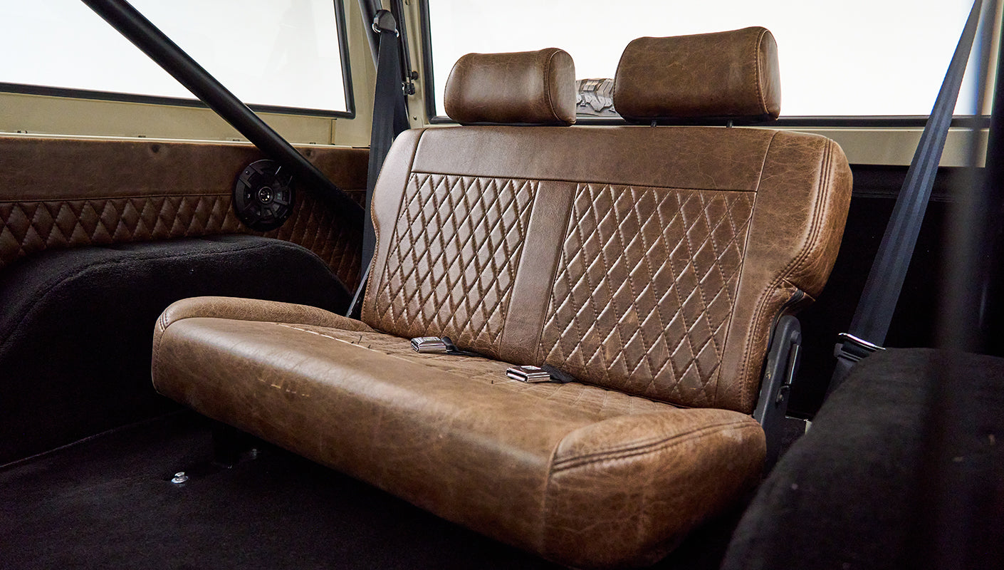 Brown leather rear bench seat with diamond stitching and seat belts in Classic Ford Bronco