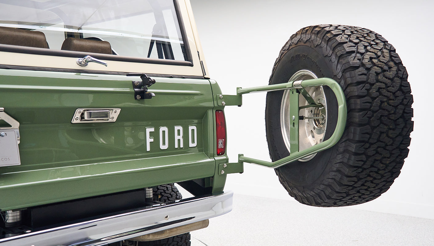 Spare tire mounted on green swing-away tailgate of Classic Ford Bronco with FORD lettering