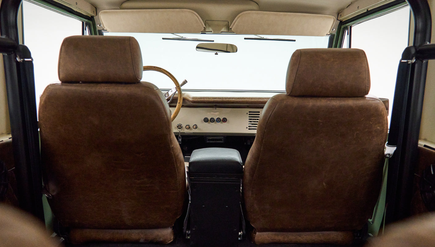 Rear view of Classic Ford Bronco front seats with textured brown leather upholstery and roll bar