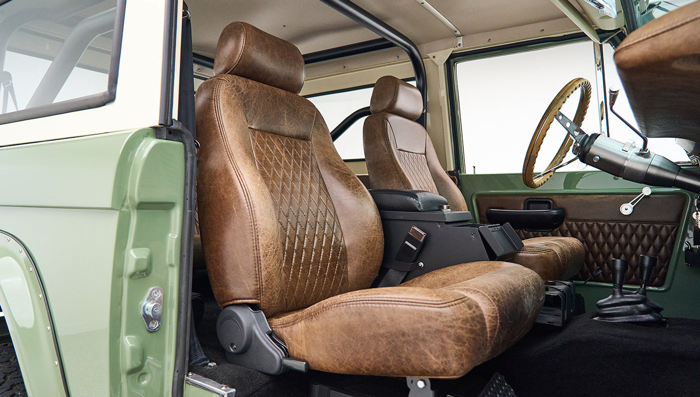Interior view of classic Ford Bronco showing driver's and passenger's brown leather seats with diamond stitching.