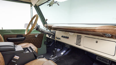 Classic Ford Bronco interior with green door panel, textured brown leather seats, and dashboard