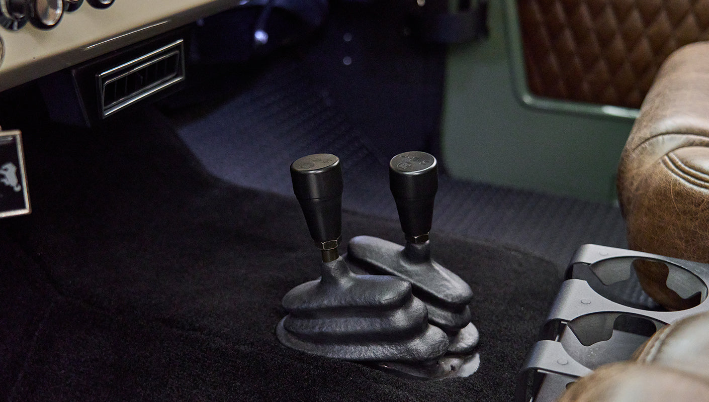 Close-up of two black gear shift levers on black carpet in Classic Ford Bronco interior