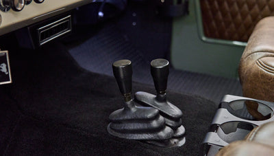 Close-up of two black gear shift levers on black carpet in Classic Ford Bronco interior