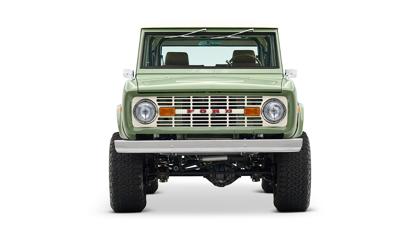 Classic Ford Bronco in boxwood green with white roof, front profile on white backdrop.