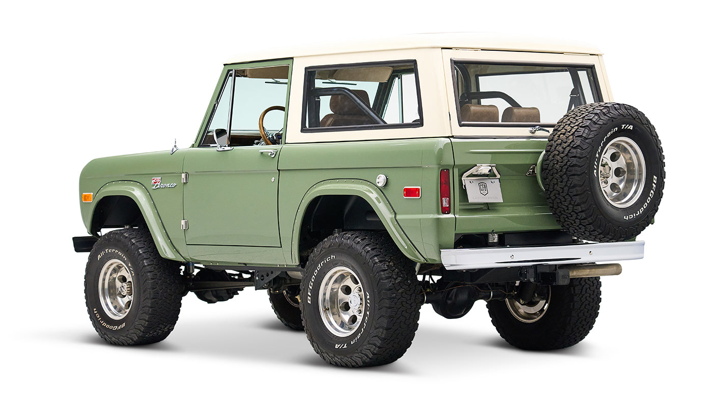Classic Ford Bronco in boxwood green with white roof, angled rear view on white background.