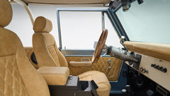 Beige leather front seats with center console and open door of Classic Ford Bronco