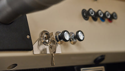 Ignition switch with key inserted and three black control knobs on Classic Ford Bronco dashboard.