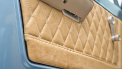 Close-up of beige diamond-stitched upholstery on door panel in Classic Ford Bronco.