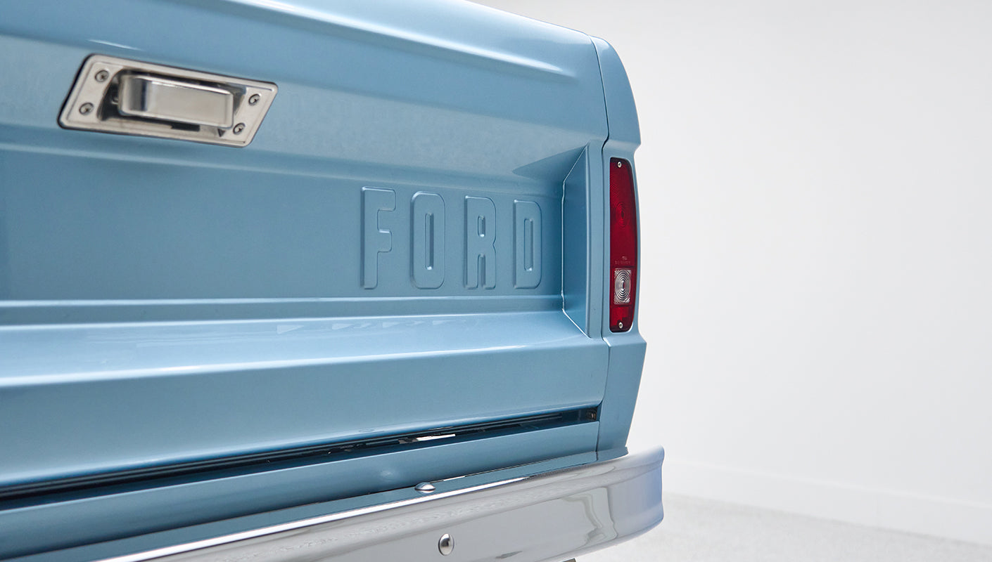 Close-up of Classic Ford Bronco rear tailgate area in light blue with FORD embossed and tail light