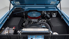 Engine compartment of a Classic Ford Bronco showing a blue engine bay with a round air filter and battery