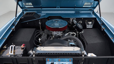 Engine compartment of a Classic Ford Bronco showing a blue engine bay with a round air filter and battery