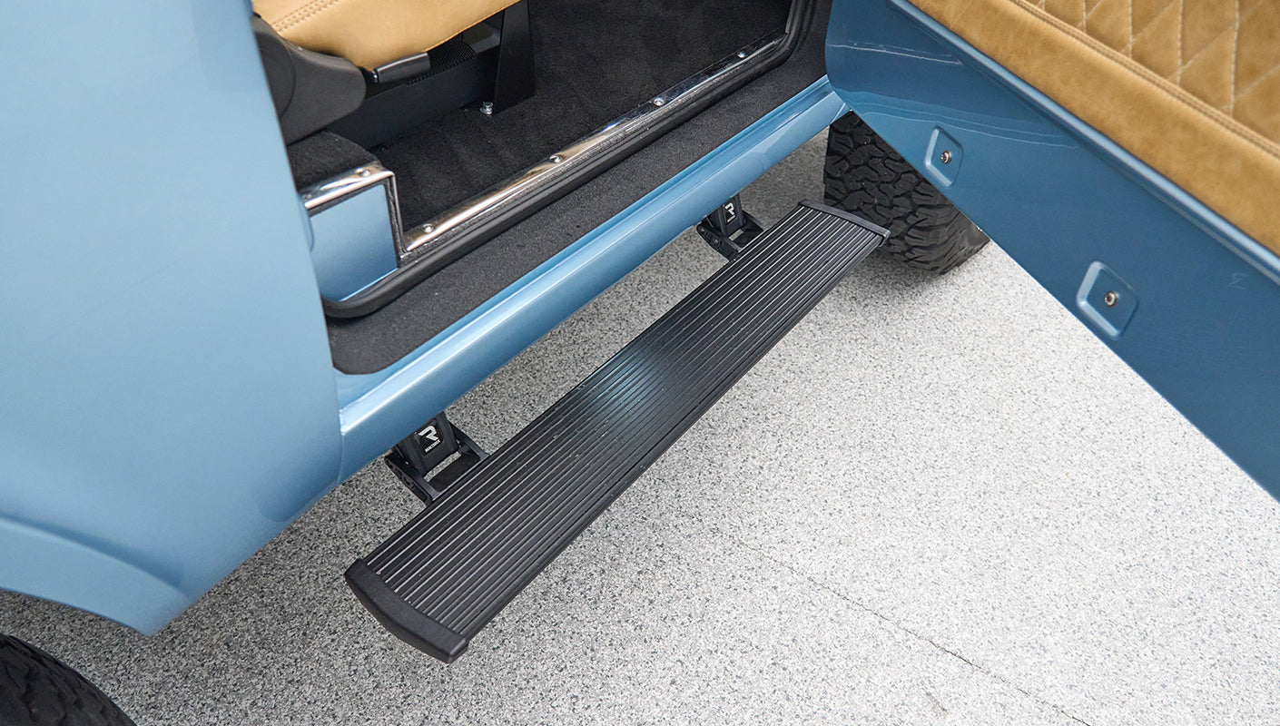 Metal black side step extended from open door on light blue Classic Ford Bronco
