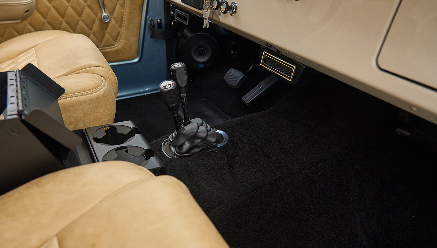 Front interior floor area of Classic Ford Bronco with two gear shifters and tan seats