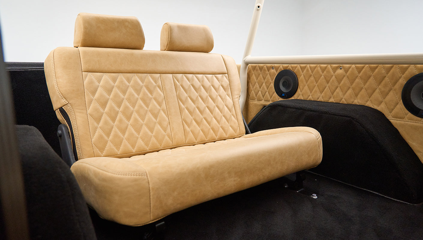 Another angle of beige leather rear bench seat with speakers on interior panel inside Classic Ford Bronco