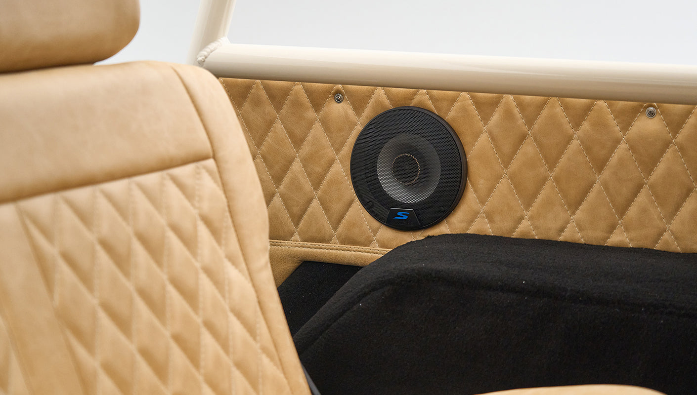 Close-up of tan quilted upholstery and black speaker cover on side panel inside Classic Ford Bronco