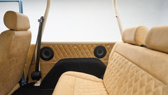 Interior rear seats of Classic Ford Bronco with tan quilted upholstery and black speaker covers on side panels