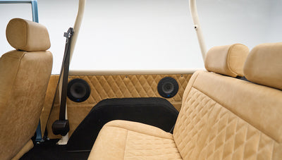 Interior rear seats of Classic Ford Bronco with tan quilted upholstery and black speaker covers on side panels