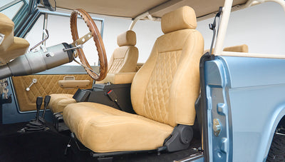 Beige leather front seats and wood steering wheel inside Classic Ford Bronco