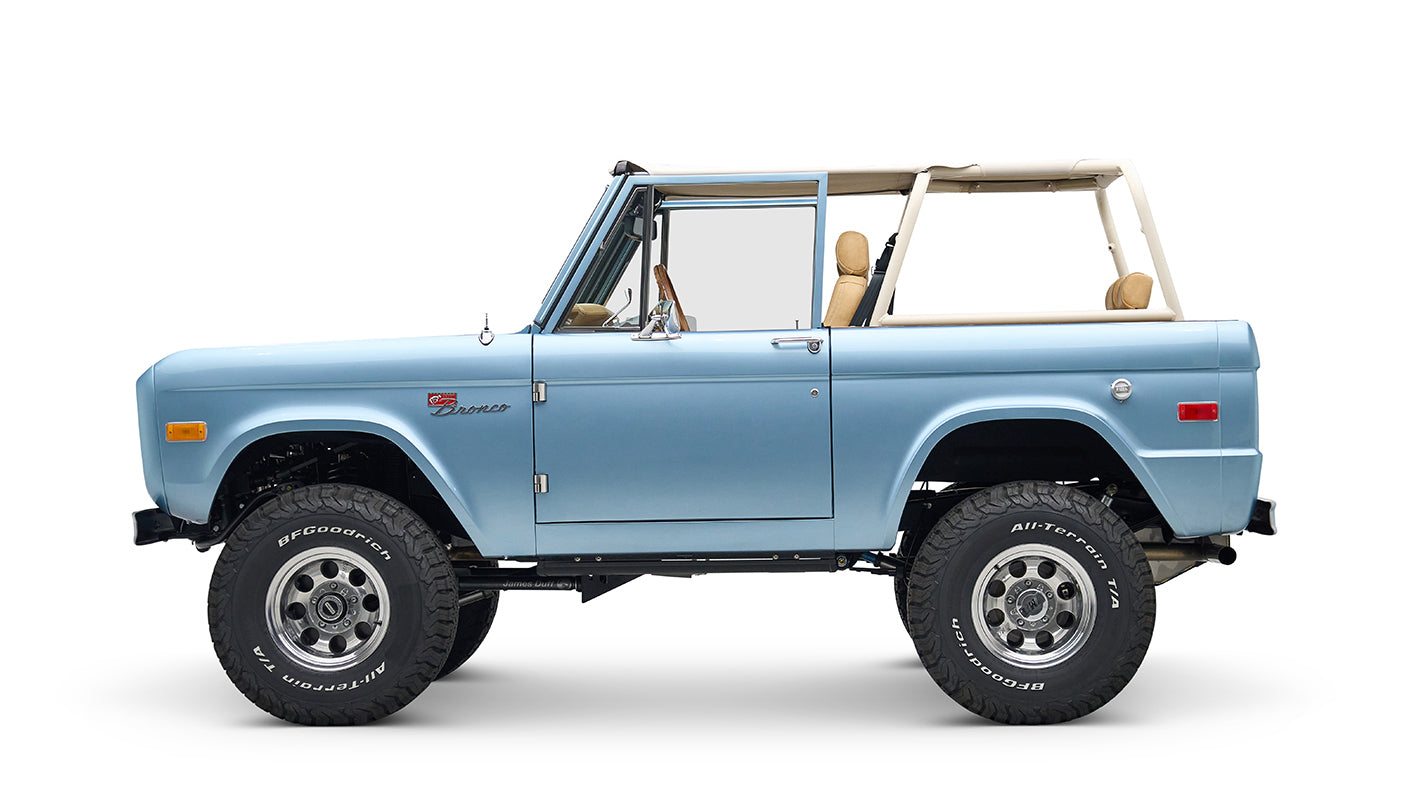 Side profile of light blue Classic Ford Bronco without roof, tan interior visible