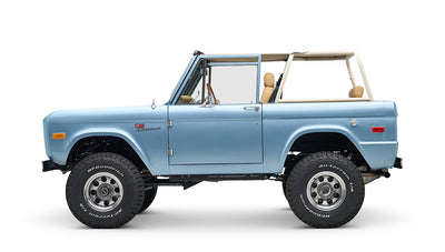 Side profile of light blue Classic Ford Bronco without roof, tan interior visible