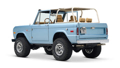 Light blue Classic Ford Bronco with beige roll cage, three-quarter right rear view showing tailgate