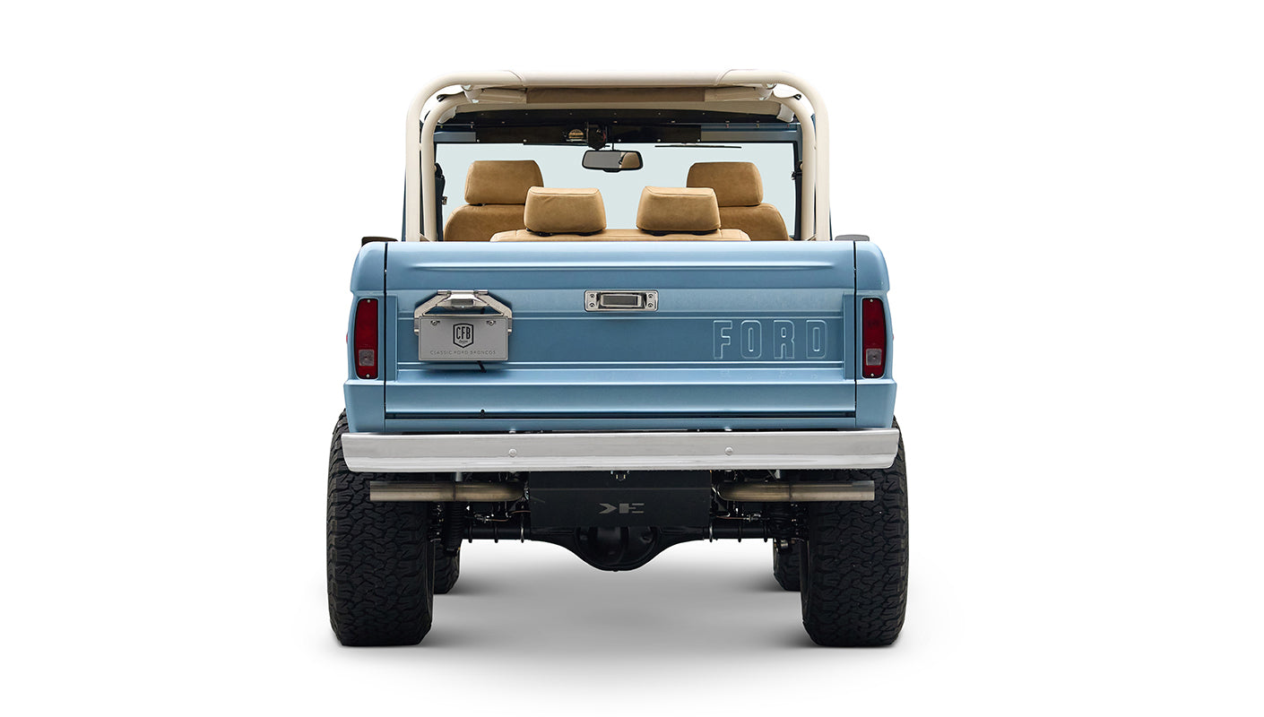 Rear view of light blue Classic Ford Bronco with large tires and FORD embossed tailgate