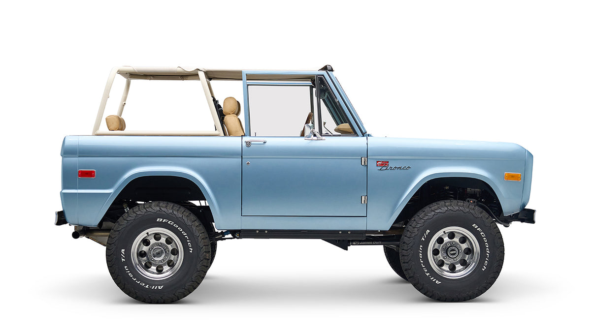 Side profile of light blue Classic Ford Bronco with beige roll cage, no roof