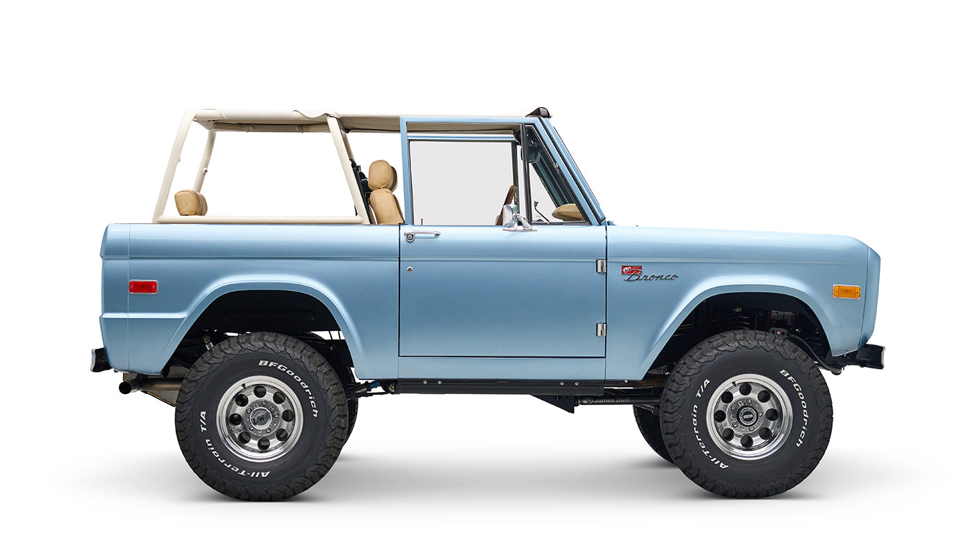 Side profile of light blue Classic Ford Bronco with beige roll cage, no roof