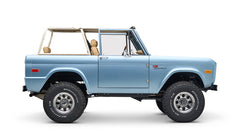 Side profile of light blue Classic Ford Bronco with beige roll cage, no roof