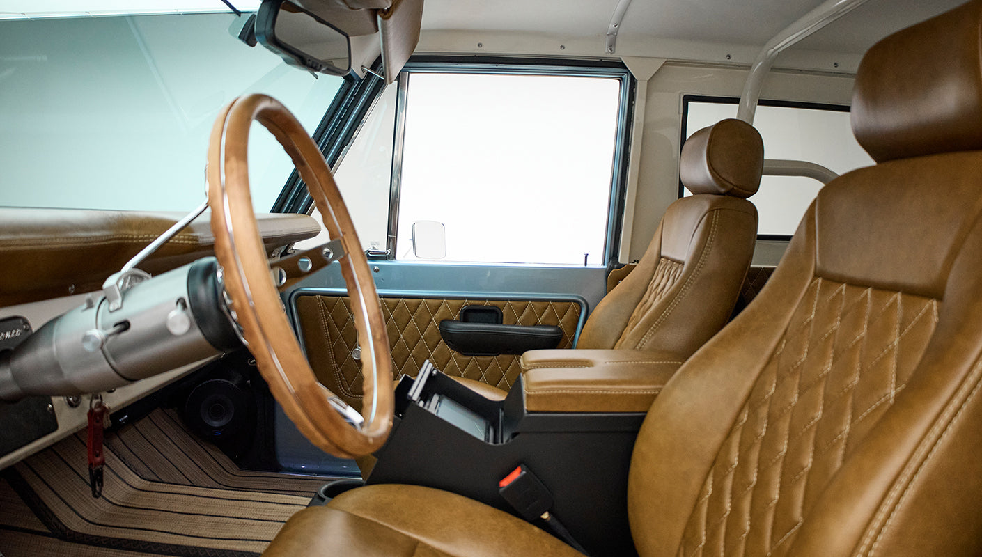 Interior view showing brown leather seats and wood steering wheel inside Classic Ford Bronco
