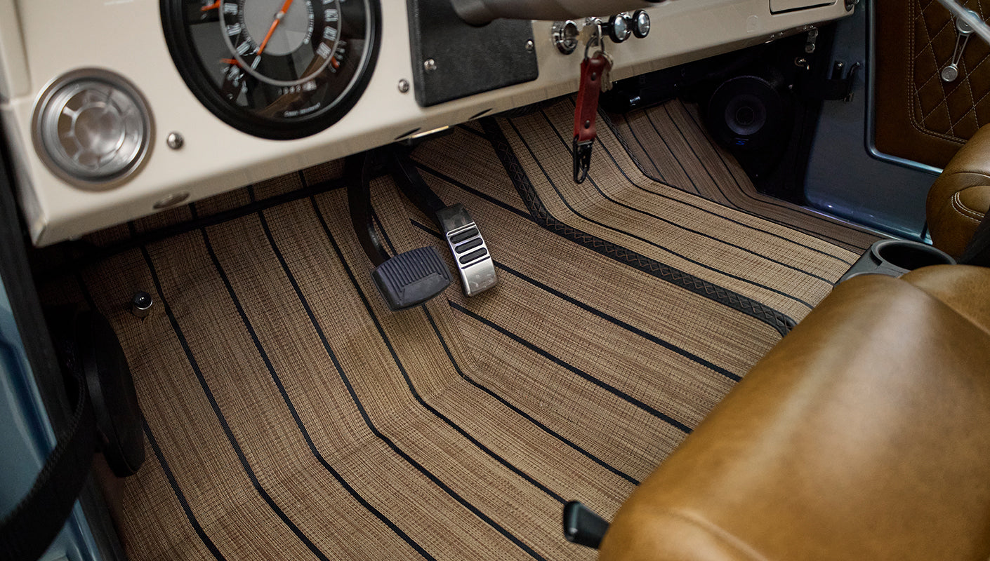 Floor area featuring pedals and brown striped floor mats in Classic Ford Bronco interior